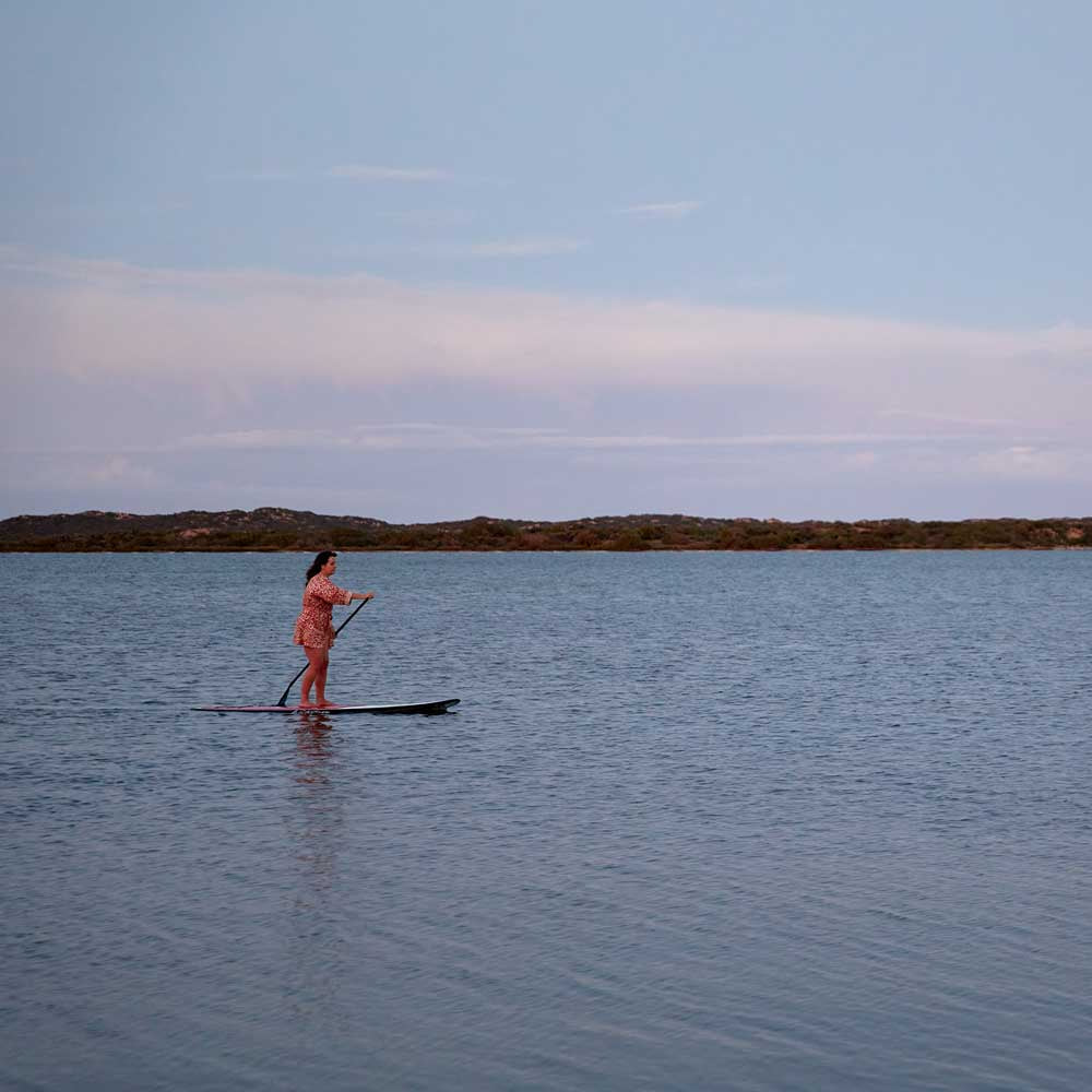 Women on paddle boarding on a calm coorong waters with a clear sky Coorong Life
