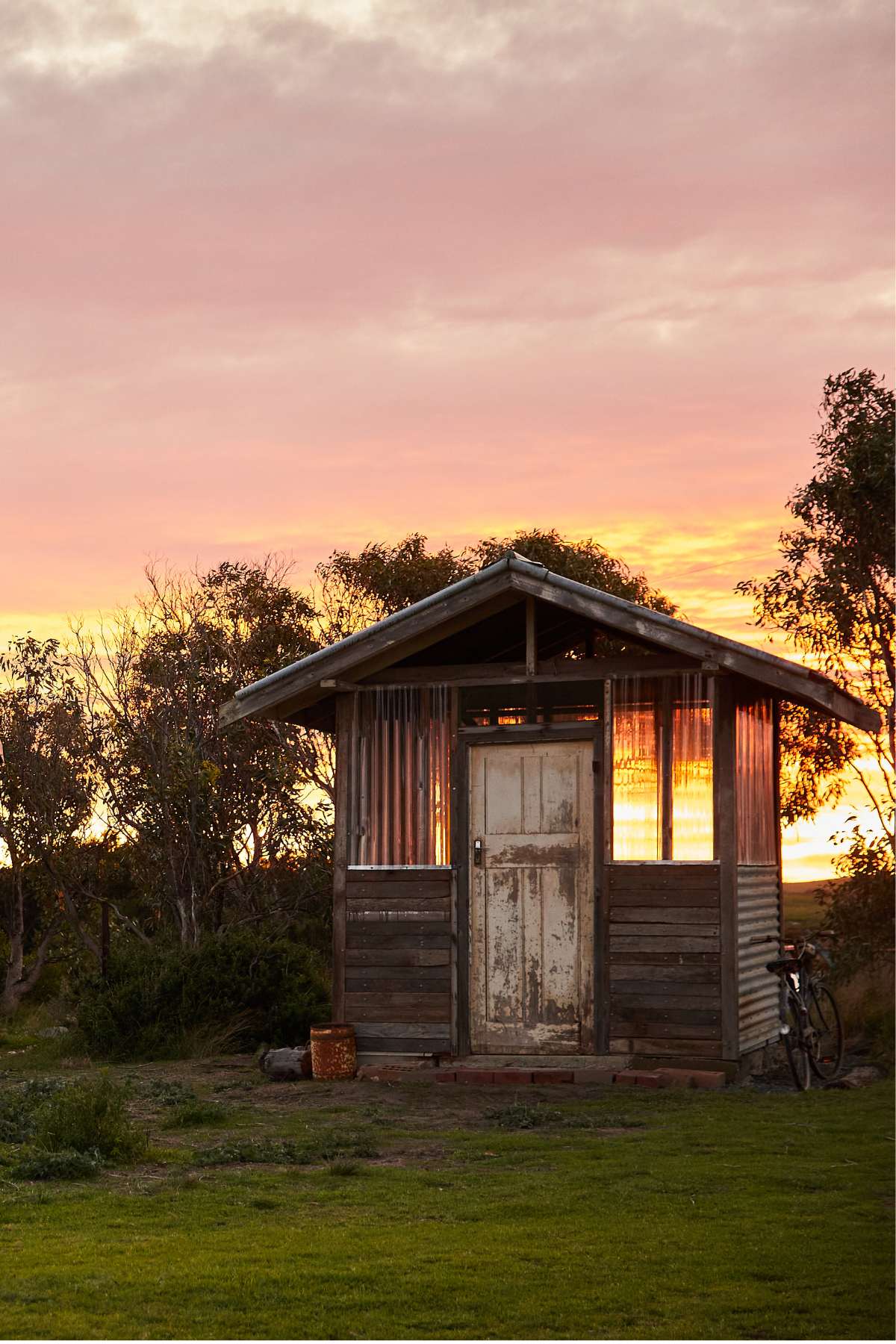 Wooden cabin in a field with a sunset sky at Coorong.life 