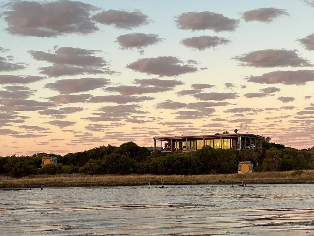 Coorong life Main building and KipPod  by a body of water with a sunset sky and KipPod II 